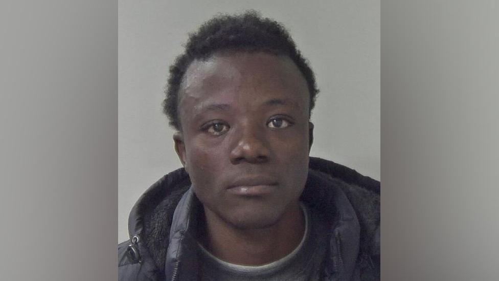 Mugshot of Ibrahima Bah. He is looking directly at the camera and is wearing a dark coloured jumper and coat. 