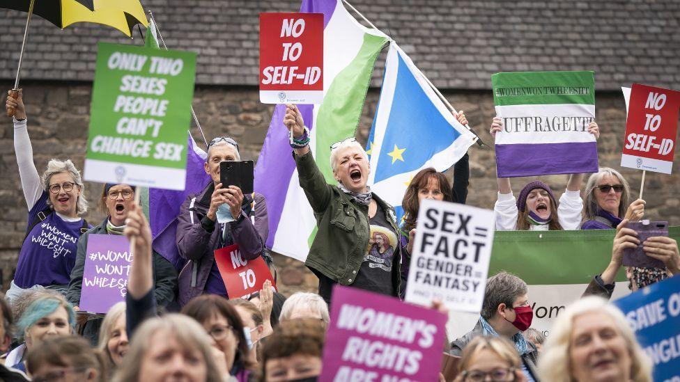 Gender critical campaigners, holding multi-coloured signs, protest outside the Scottish Parliament 