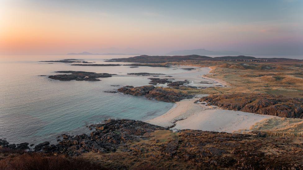 Pastel sky of blue and orange over a blue sea and beach at Sanna, Ardnamurchan.