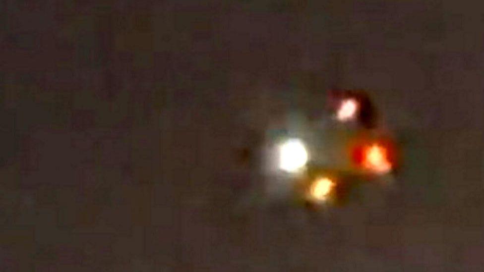 Fuzzy, multi-coloured lights are seen amid a dark background in a zoomed-in and unclear photo 