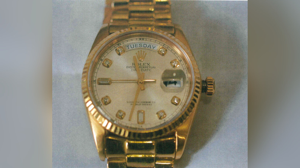 A picture of a gold Rolex watch against a plain background.