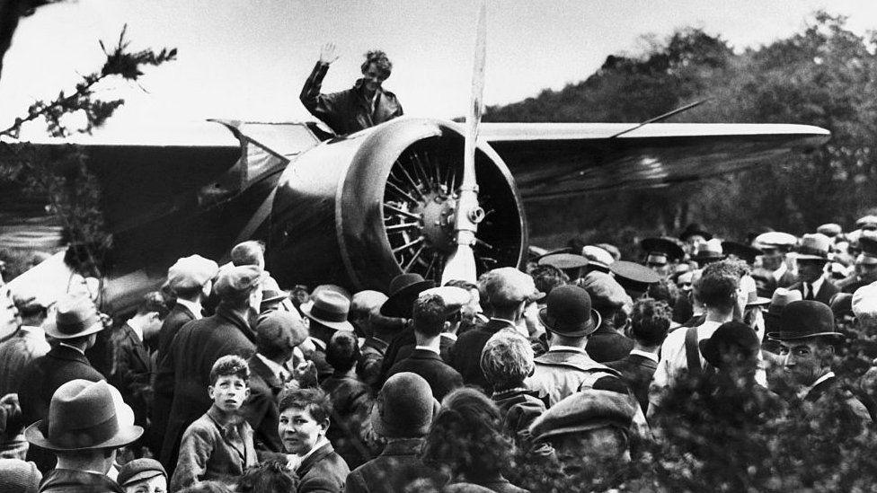 Pilot Amelia Earhart sitting in her plane, which is surronded by a crowd of onlookers, as she prepares for take off, from a field on the outskirts of Derry in 1932