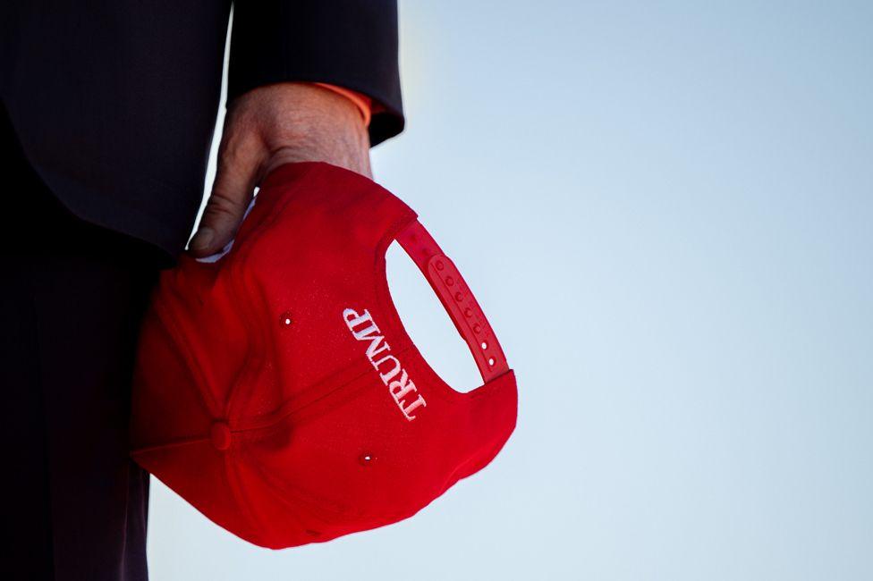 Former U.S. President Donald Trump holds his cap