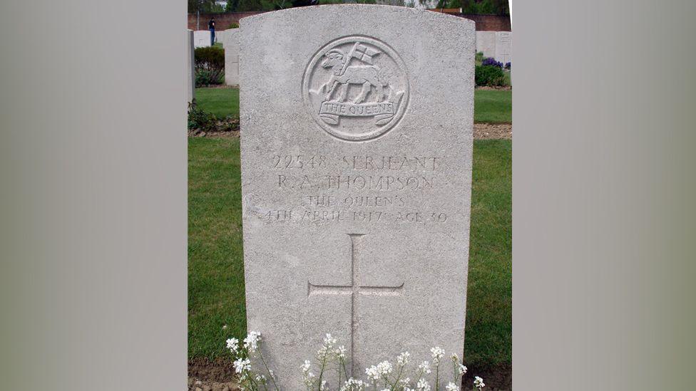 A stone grave in a graveyard. It shows the name of Sgt Thompson, his date of death and has a cross engraved on it