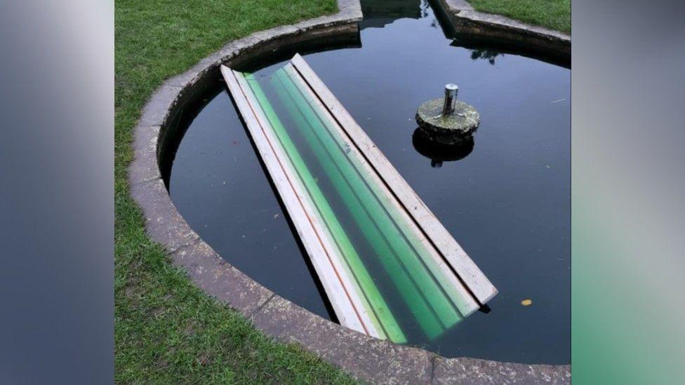 A bench is submerged in the water of a fountain.