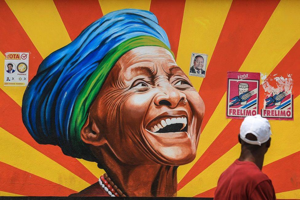 A mural of a woman's face surrounded by flyers promoting political parties - Monday 30 September 2024