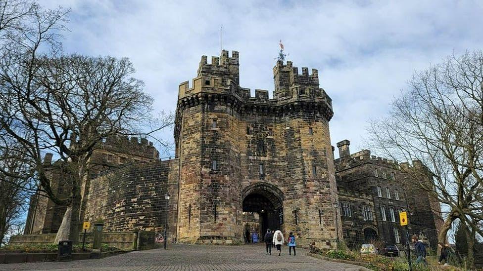 External view of the entrance to Lancaster Castle with a family walking through the arched entrance