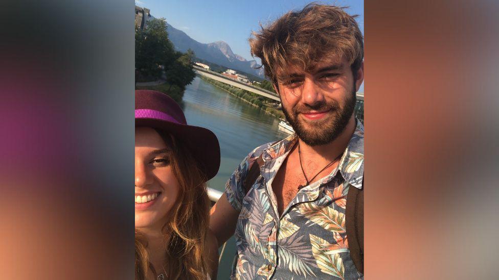 Ellie Crabb in a selfie with her fiancé Sam. They are on a bridge and there is a river behind them.