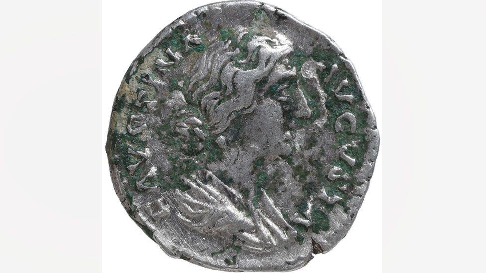 The front showing the empress Faustina. She is in profile, with hair pulled into a bun at her neck. The coin shows signs of greening. It dates to AD161-75.