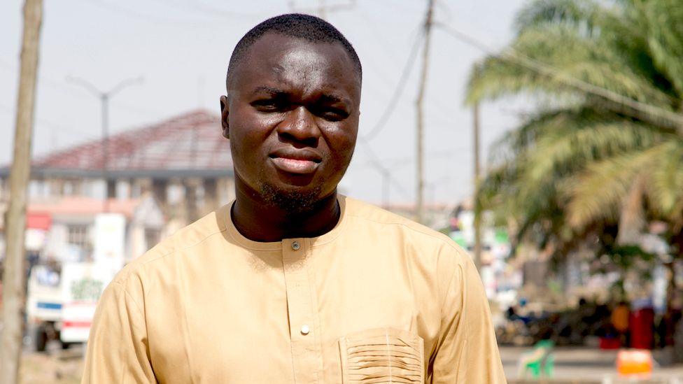 A head and shoulders shot of a man in a beige shirt staring into the sun.