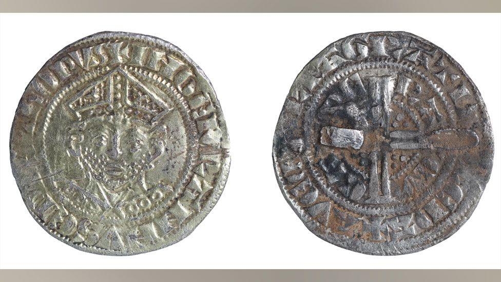 The front and back of a 13th Century silver gilt coin brooch, the front showing the face of a bishop and the back showing a cross and marks where the pin was once attached