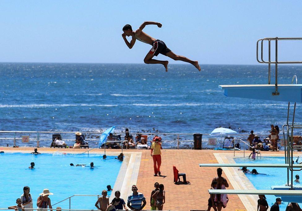 A person dives from a springboard during a hot summer day at Sea Point swimming pool in Cape Town, South Africa, January 10, 2025. 