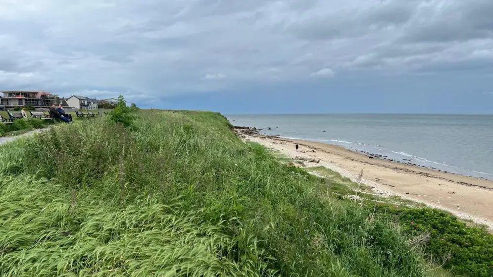 Coast where Whitburn pipe is. Greenery and sea is in the background alongside the beach. 