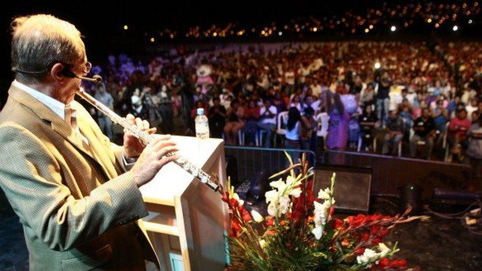 Peruvian presidential candidate for the Alliance for the Big Change party, Pedro Pablo Kuczynski, plays the transverse flute before a crowd at the shantytown 'My Peru', in the district of Ventanilla, Callao, as part of his electoral campaign towards the April 10 presidential campaign, on March 14, 2011.