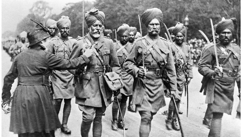 A woman pins flowers on to the tunic of an Indian soldier