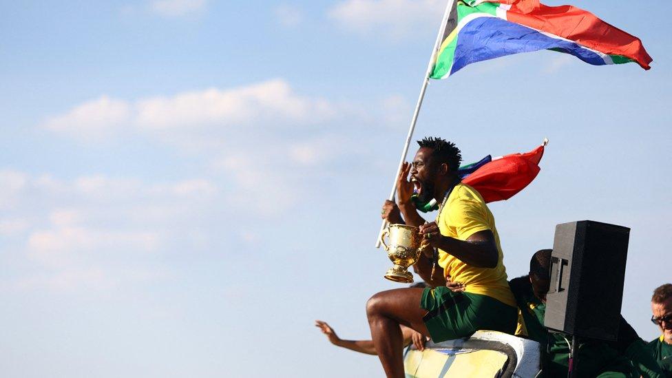 South Africa's Siya Kolisi celebrates winning the World Cup with teammates on the bus during the trophy tour