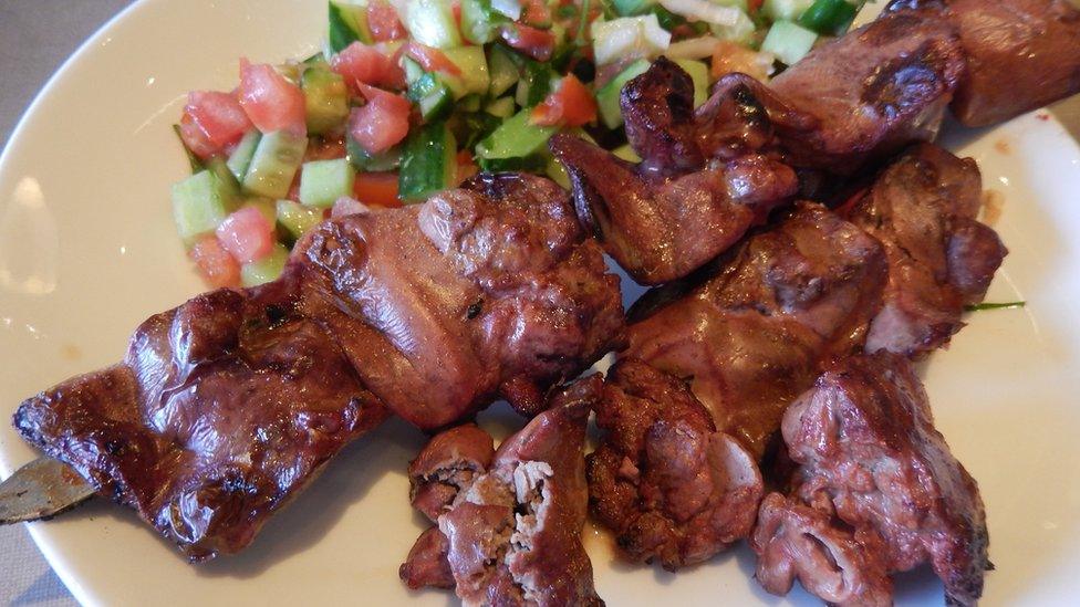 Kosher meat, chicken hearts and livers skewers, a top iron-rich food, with tomato and cucumber salad, close-up - stock photo