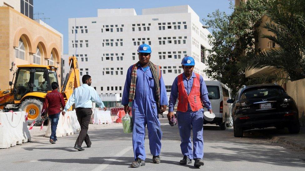 Migrant workers walk next to a construction site in Doha, Qatar (6 December 2016)