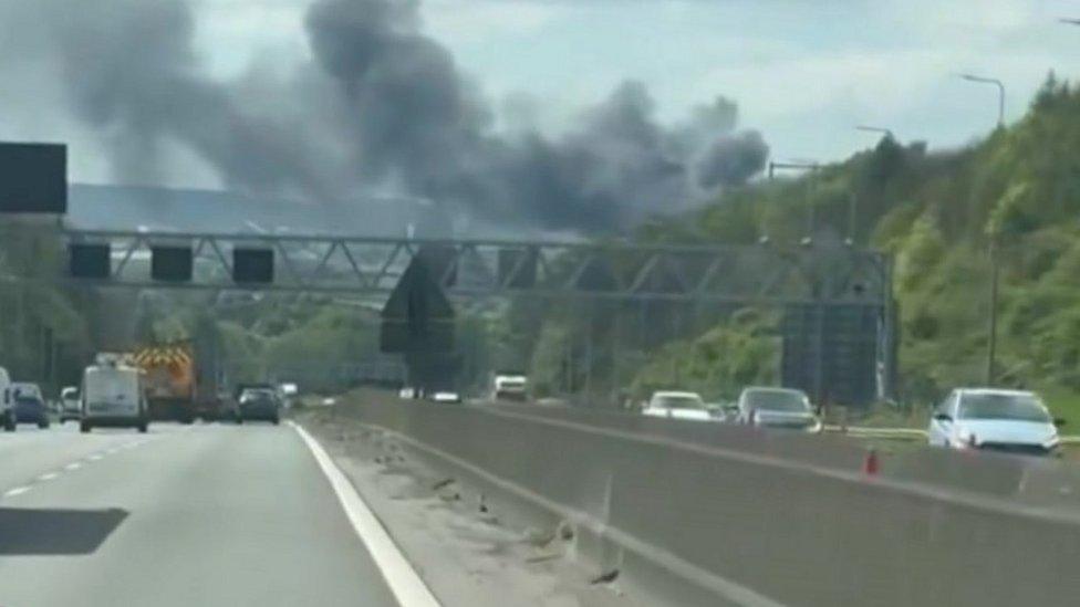 Motorway with cars driving on it and dark smoke in the distance