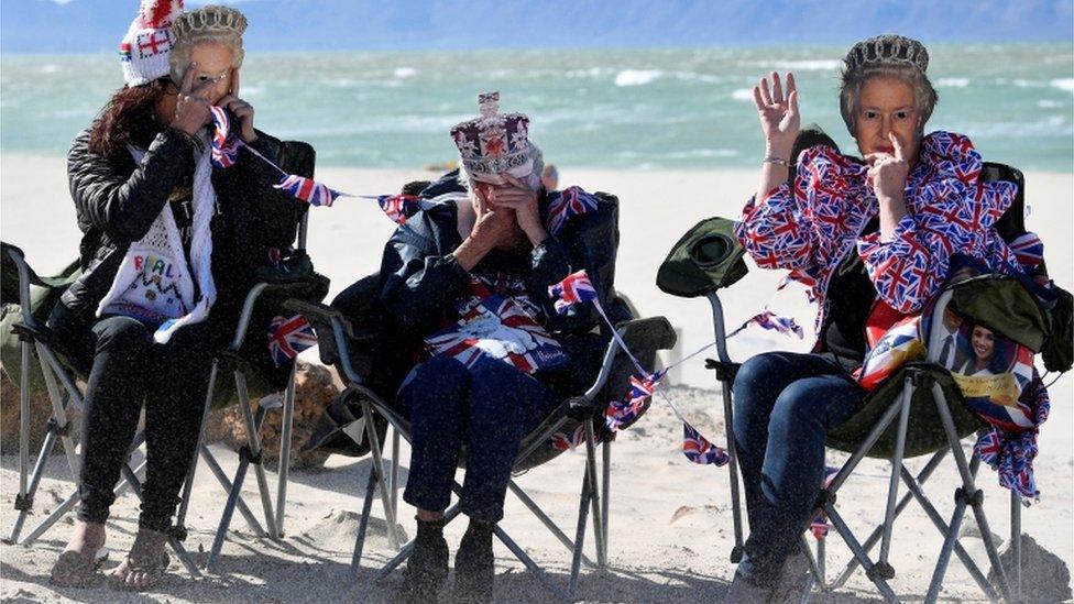 People hold up masks depicting Britain's Queen Elizabeth