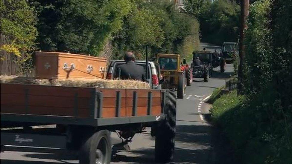 A convoy of tractors are used to lead a man's coffin to his funeral