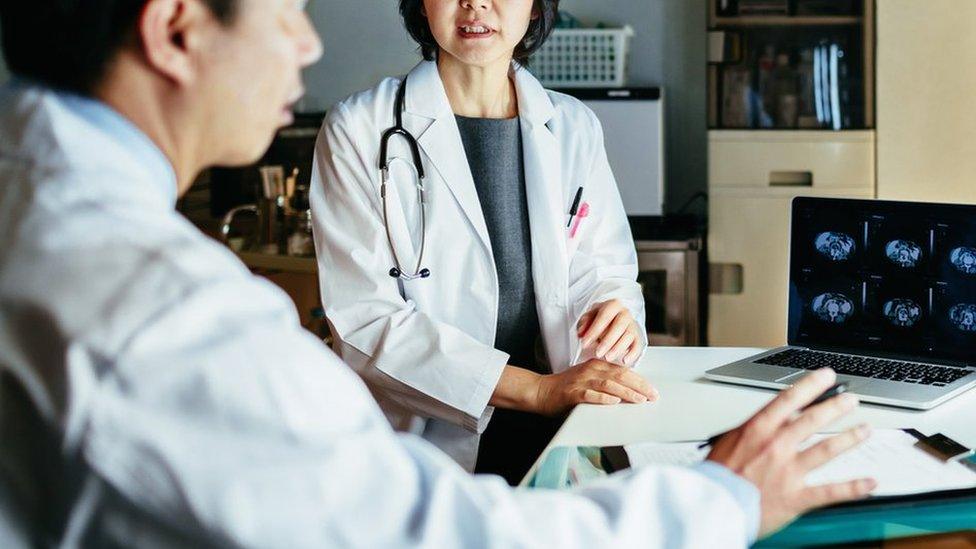 Stock image of a male and female doctor looking at MRI scans in an office