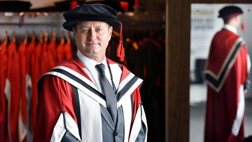 George Clarke wearing a university robe