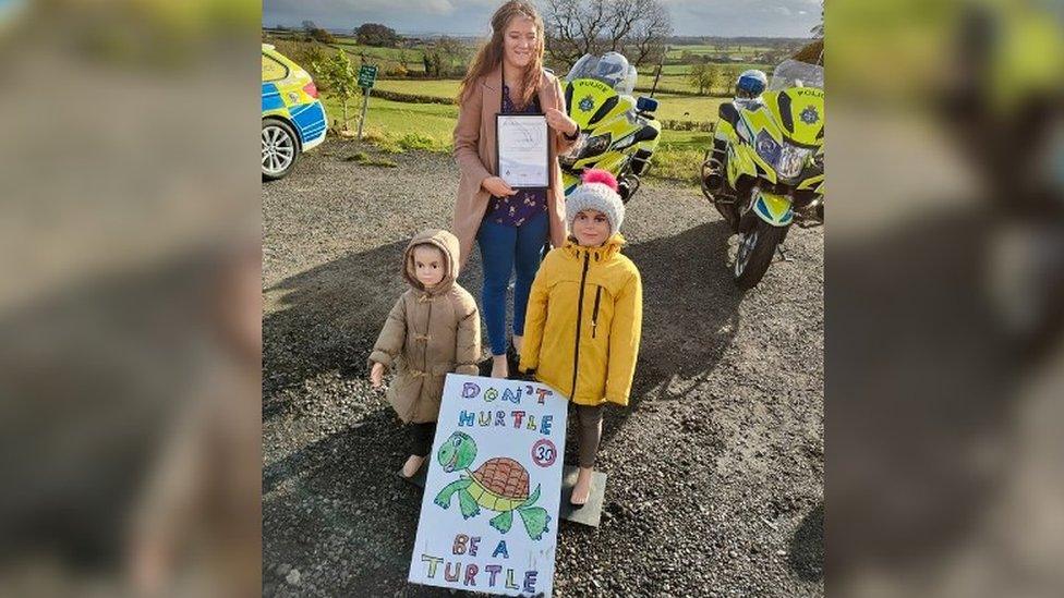 Erin with two child mannequins and her certificate