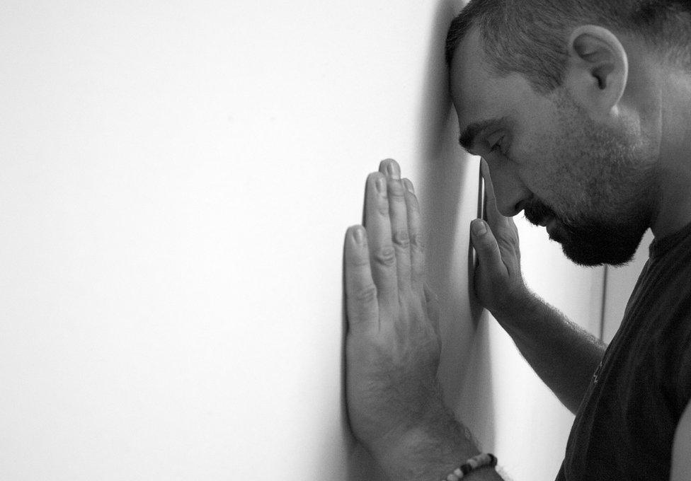 Man puts head against a wall