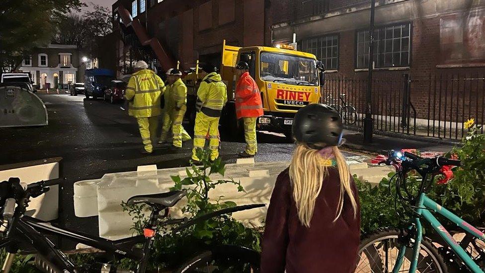 Girl looks on at contractors walking away