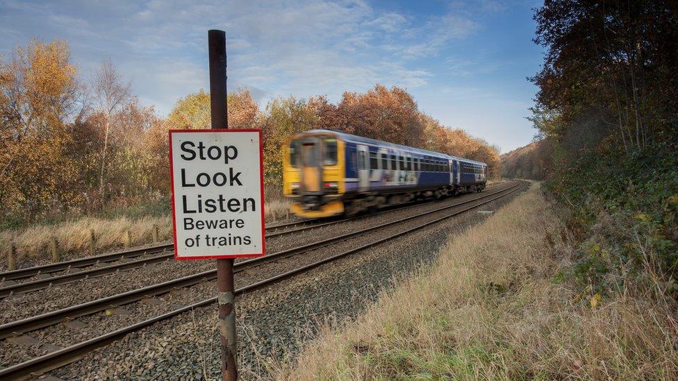 Train tracks with a sign saying "Stop Look Listen Beware of trains"