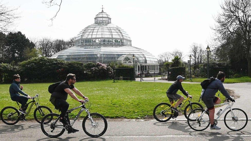 People cycle past Victorian Palm House in Sefton Park