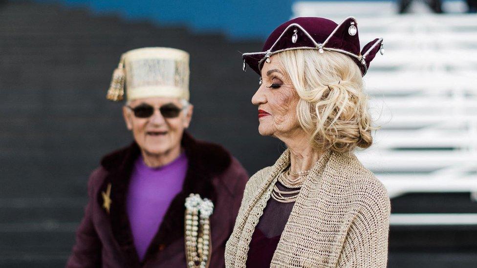 A couple walks as members of the public and models present creations by local designers during a fashion show at the 2022 editon of the Durban July horse race in Durban on July 2, 2022.