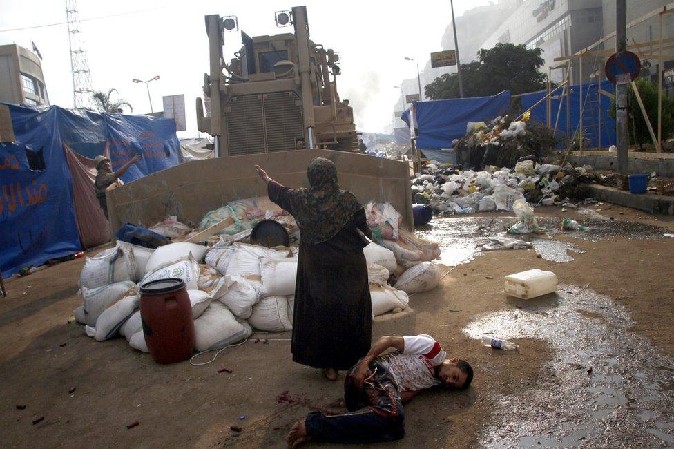 An Egyptian woman tries to stop a military bulldozer from hurting a wounded youth during clashes in Rabaa al-Adawiya square in Cairo on 14 August 2013