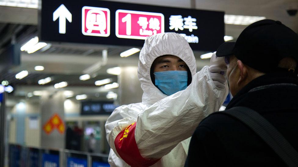 A health worker checks the temperature of a man in Beijing