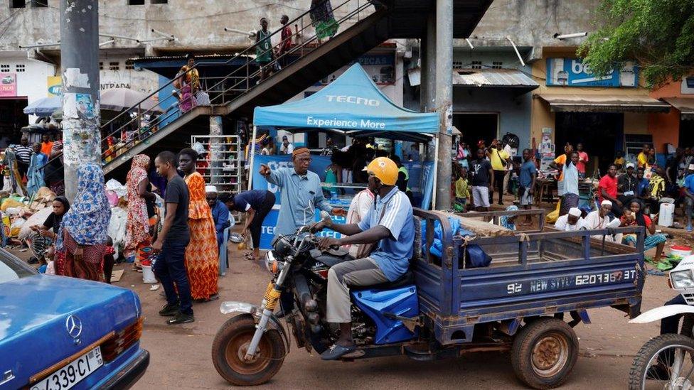 People walk and shop in the street of Bissau, on July 28, 2022