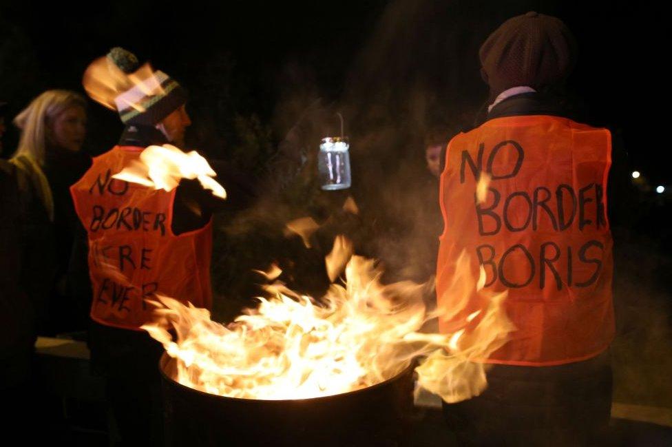 Anti-Brexit protesters standing beside a burning barrel on the Irish border