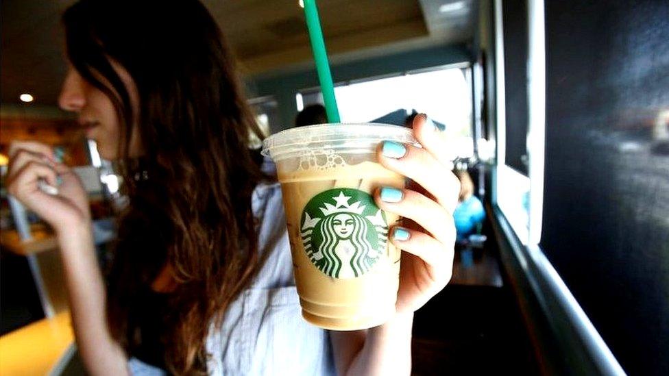 A patron holds an iced beverage with a straw, at a Starbucks coffee store in Pasadena, California