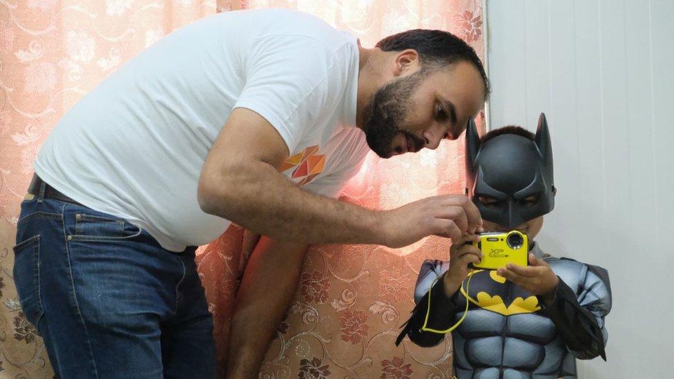 Charity worker with child refugee dressed as Batman