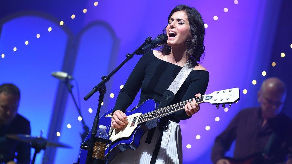 Singer Katie Melua performs with her guitar and singing into a microphone on stage