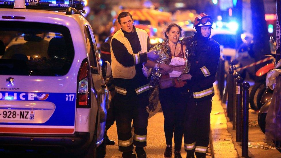 Rescue workers help a woman after a shooting, outside the Bataclan theatre in Paris