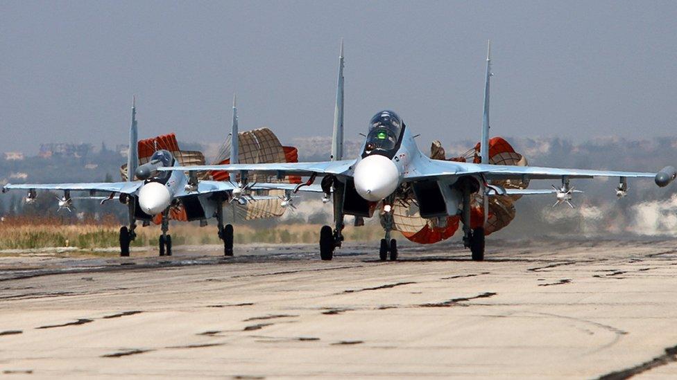 A picture taken on October 3, 2015 shows Russian Sukhoi SU-30 SM jet fighters landing on a runway at the Hmeimim airbase in the Syrian province of Latakia