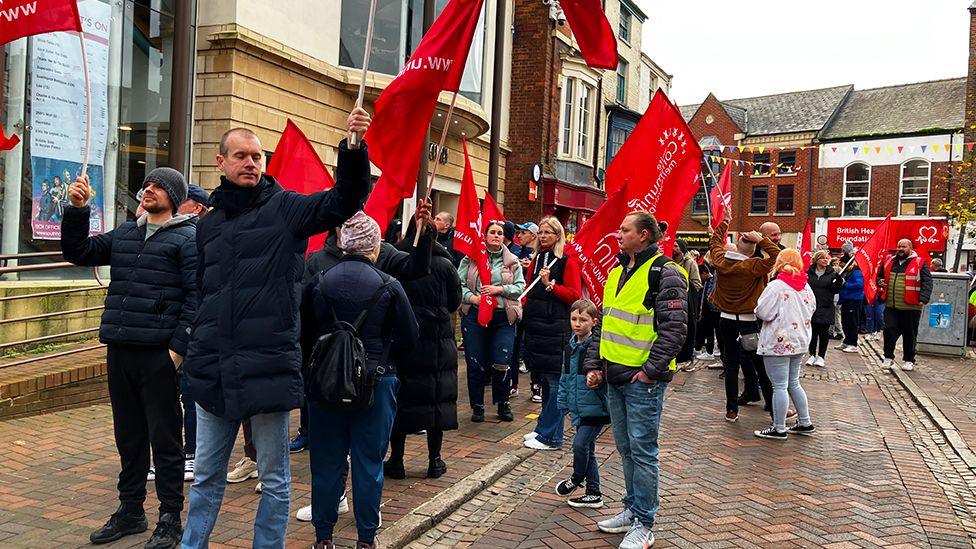 Striking workers marching through the town of Spalding waving red union flags