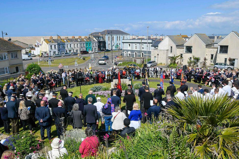 People attend a remembrance service at the American war memorial in Victoria Gardens on the Isle of Portland in Dorset.