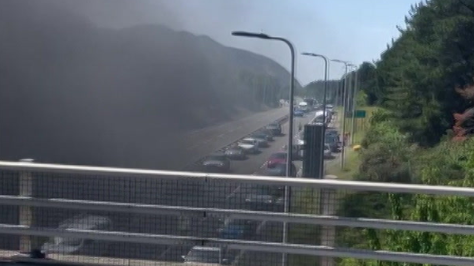 Smoke seen rising from tunnel seen from bridge above and cars stuck in queue