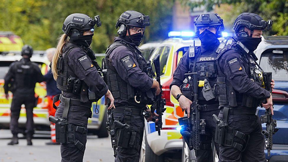Armed police officers at the scene near the Heaton Park Hebrew Congregation synagogue in Crumpsall, Manchester, where two people died in a suspected terror attack by a man who was shot dead by police. The four officers are dressed in black, holding assault rifles and wearing helmets with face coverings drawn up over their mouths.