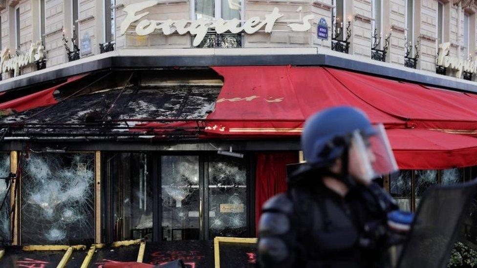 A French riot police officer stands in front of the gutted Le Fouquet's restaurant in Paris. Photo: 16 March 2019