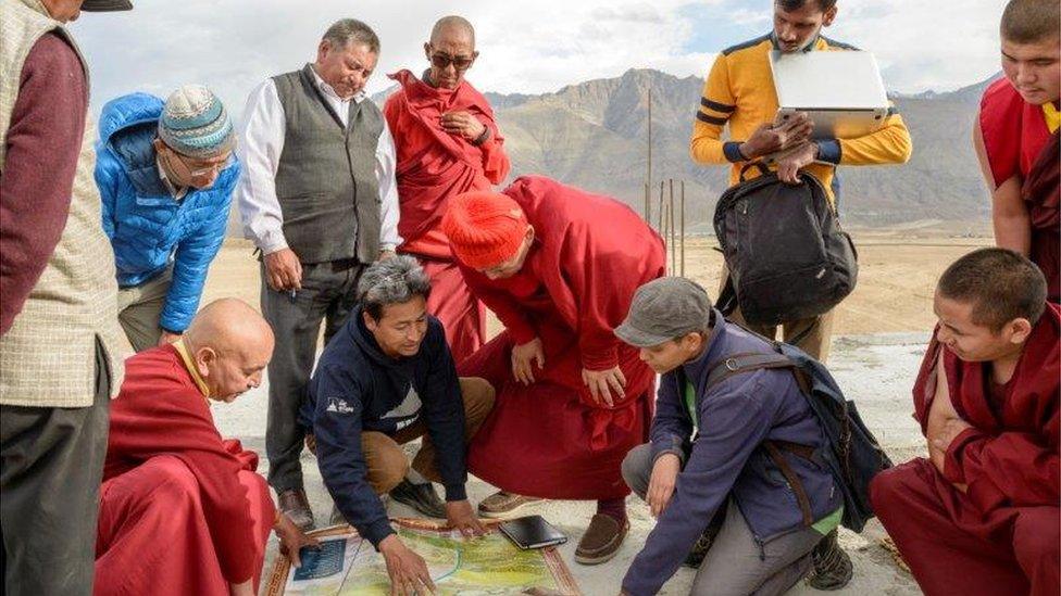 Group of people including Sonam Wangchuk gathering around ice stupa plans