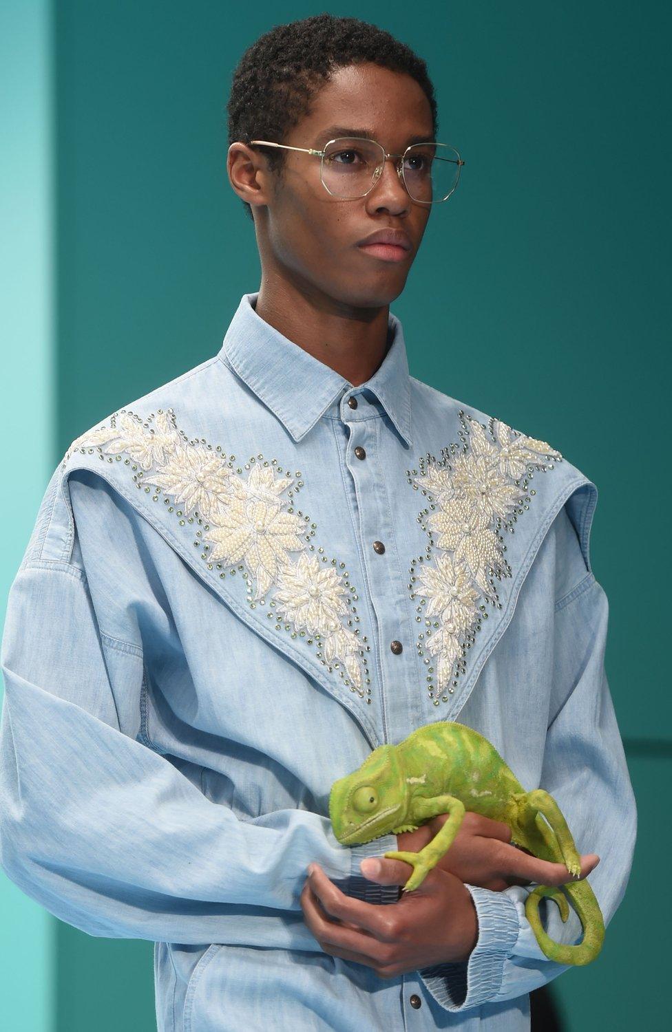 Fashion model carrying realistic-looking chameleon figure.