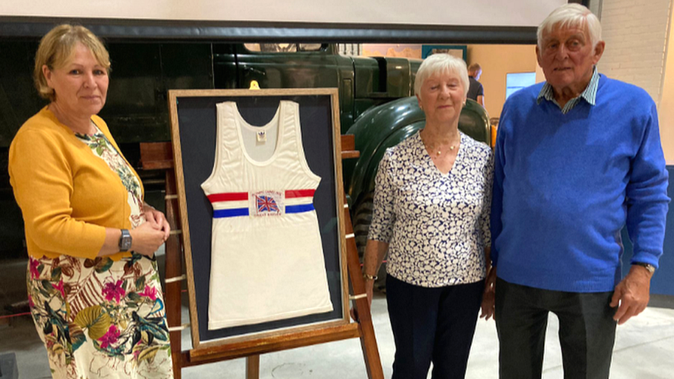 Three people standing around Jim Fox's vest